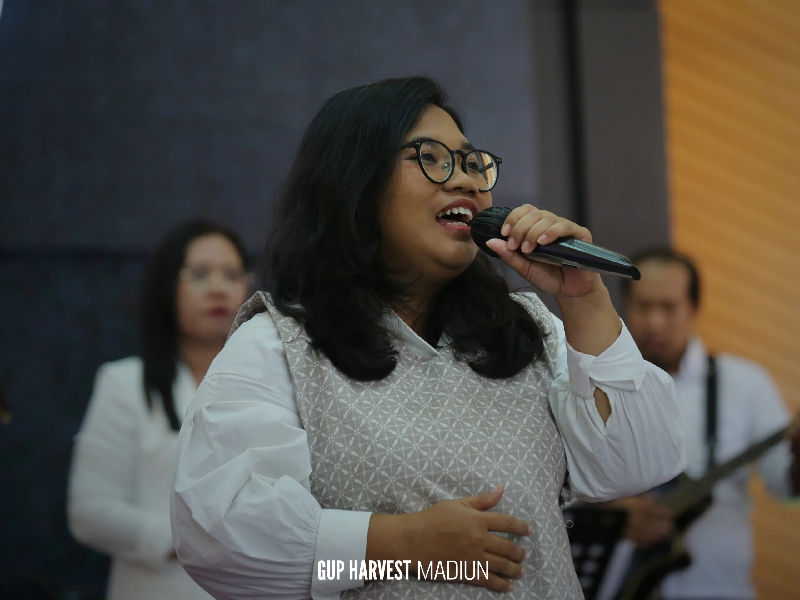 Seorang worship leader wanita memimpin pujian dengan khidmat dalam Ibadah Paskah GUP Harvest Madiun.