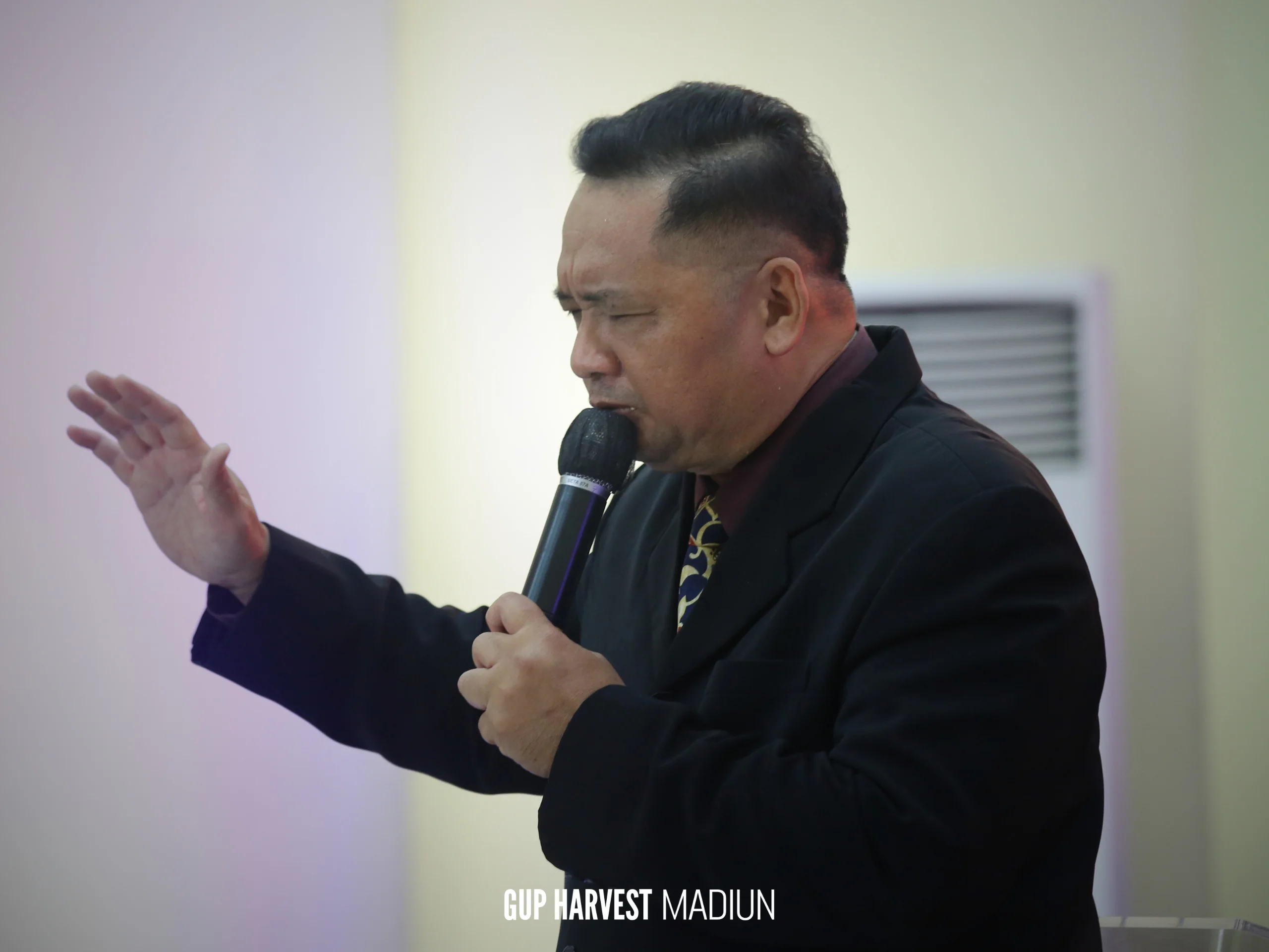 Momen khidmat saat pendeta memimpin doa dengan mengangkat tangan di atas mimbar gereja GUP Harvest.