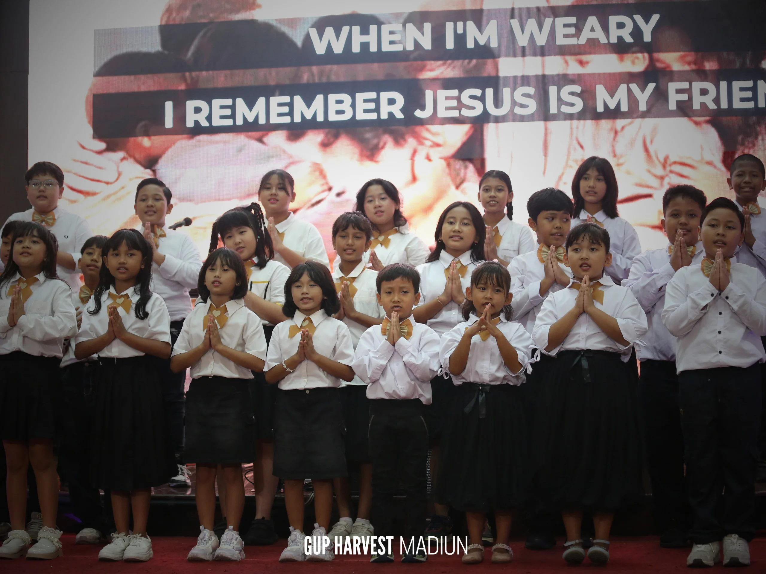 Anak-anak Sekolah Minggu GUP Harvest Madiun melipat tangan dengan khusyuk saat mempersembahkan pujian Paskah di atas panggung.