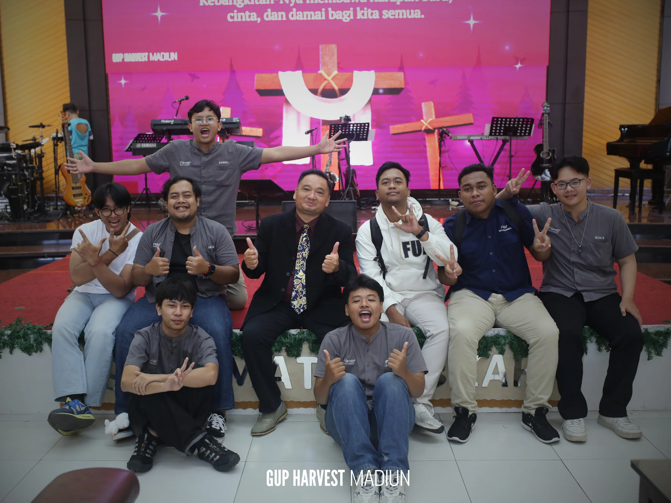 Pendeta berfoto bersama tim multimedia dan pelayan pemuda GUP Harvest Madiun dengan gaya santai yang penuh sukacita.