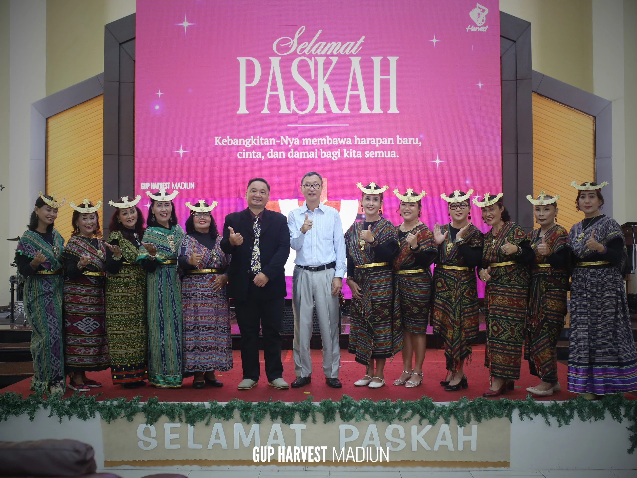 Pose jempol (thumbs up) dari gembala sidang dan pelayan wanita berbalut pakaian tradisional di panggung utama GUP Harvest.